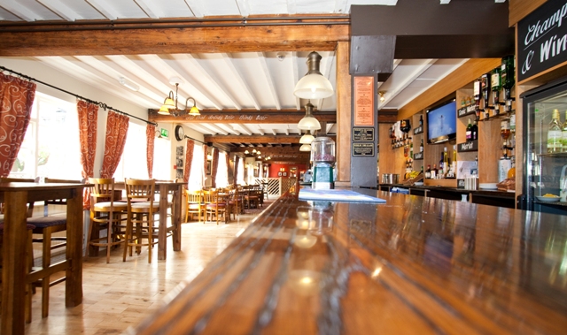 Spacious rustic venue with wooden bar, ideal for casual meetings and social events.