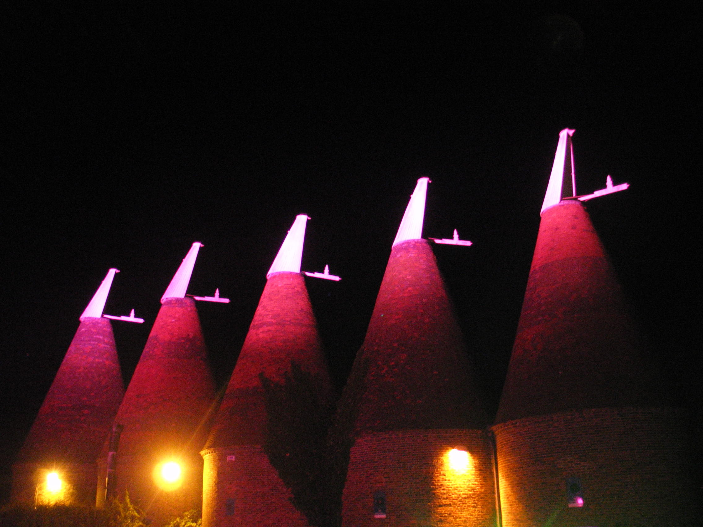 Illuminated oast houses at The Dray, a unique venue for evening events and celebrations.