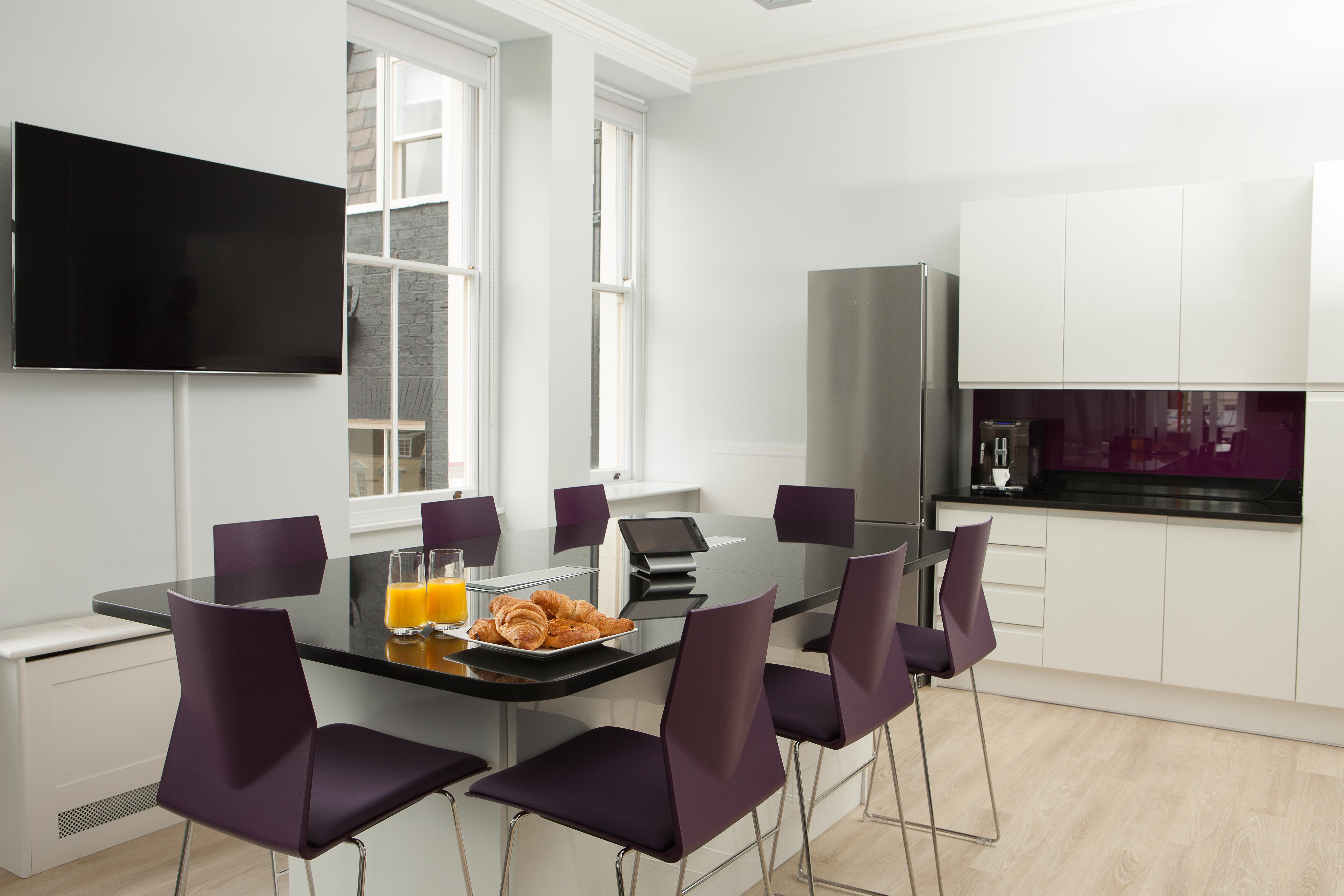 Modern meeting space with glass table and purple chairs in Mayfair for collaborative sessions.