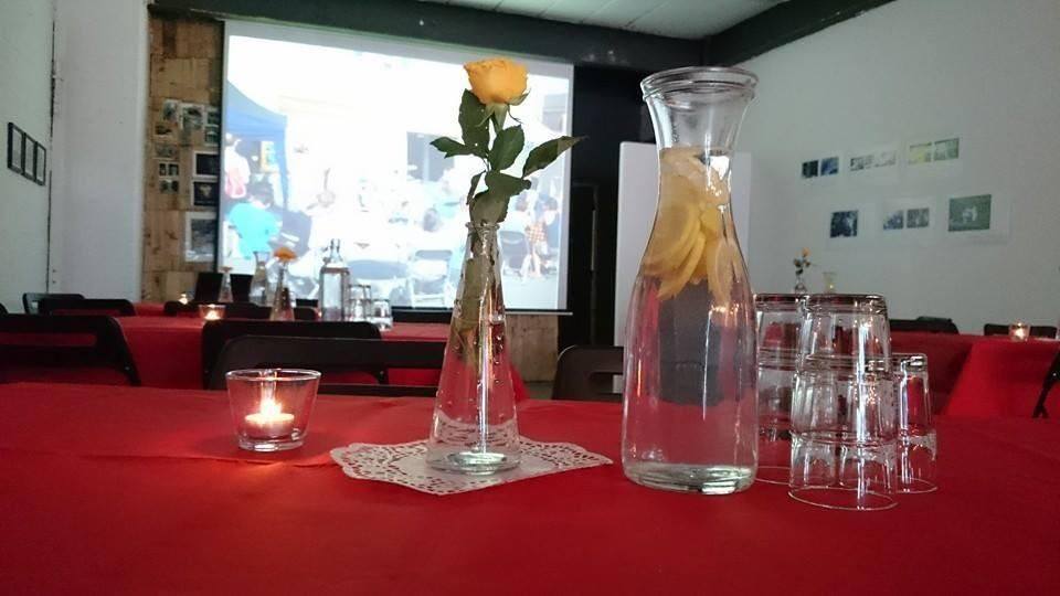 Meeting room with red tablecloths and yellow rose centerpiece for events and presentations.