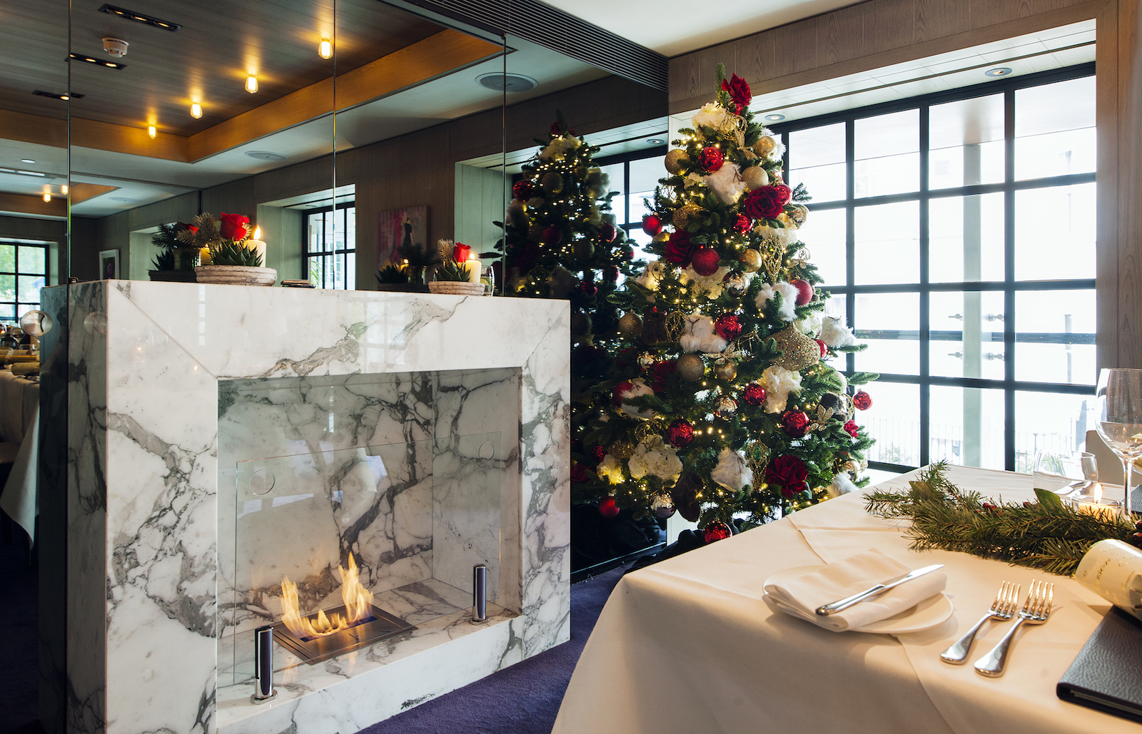Christmas party dining area with marble fireplace and festive red and white decor.