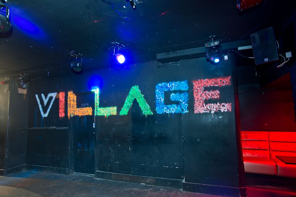 Urban venue with vibrant "VILLAGE" mural, perfect for trendy events and parties.