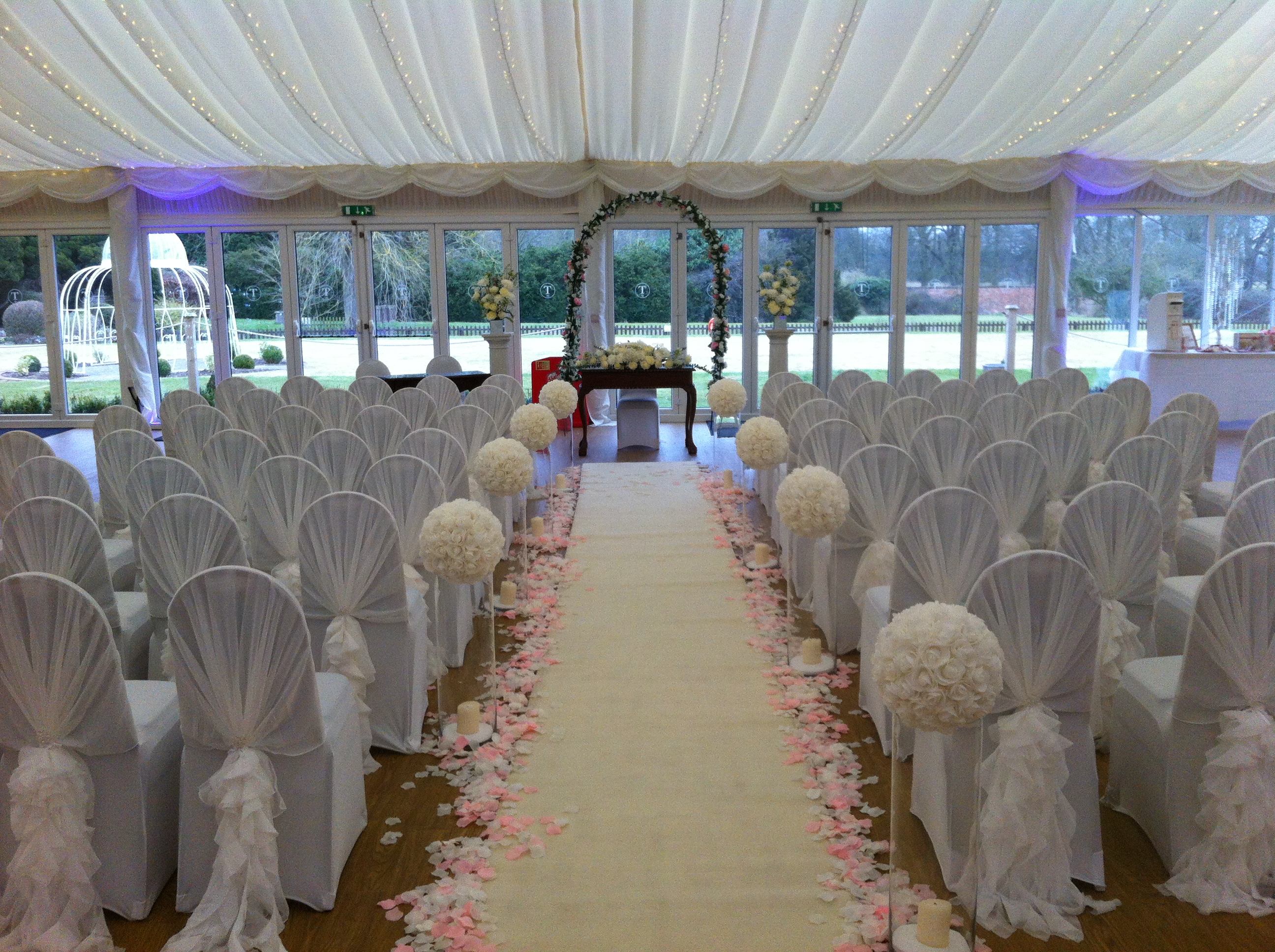 Wedding ceremony setup at Quendon Hall with floral aisle and elegant chairs.