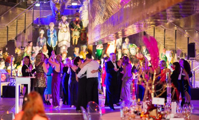 Elegant attendees dancing at The Dry Berth, Cutty Sark event space with colorful lighting.