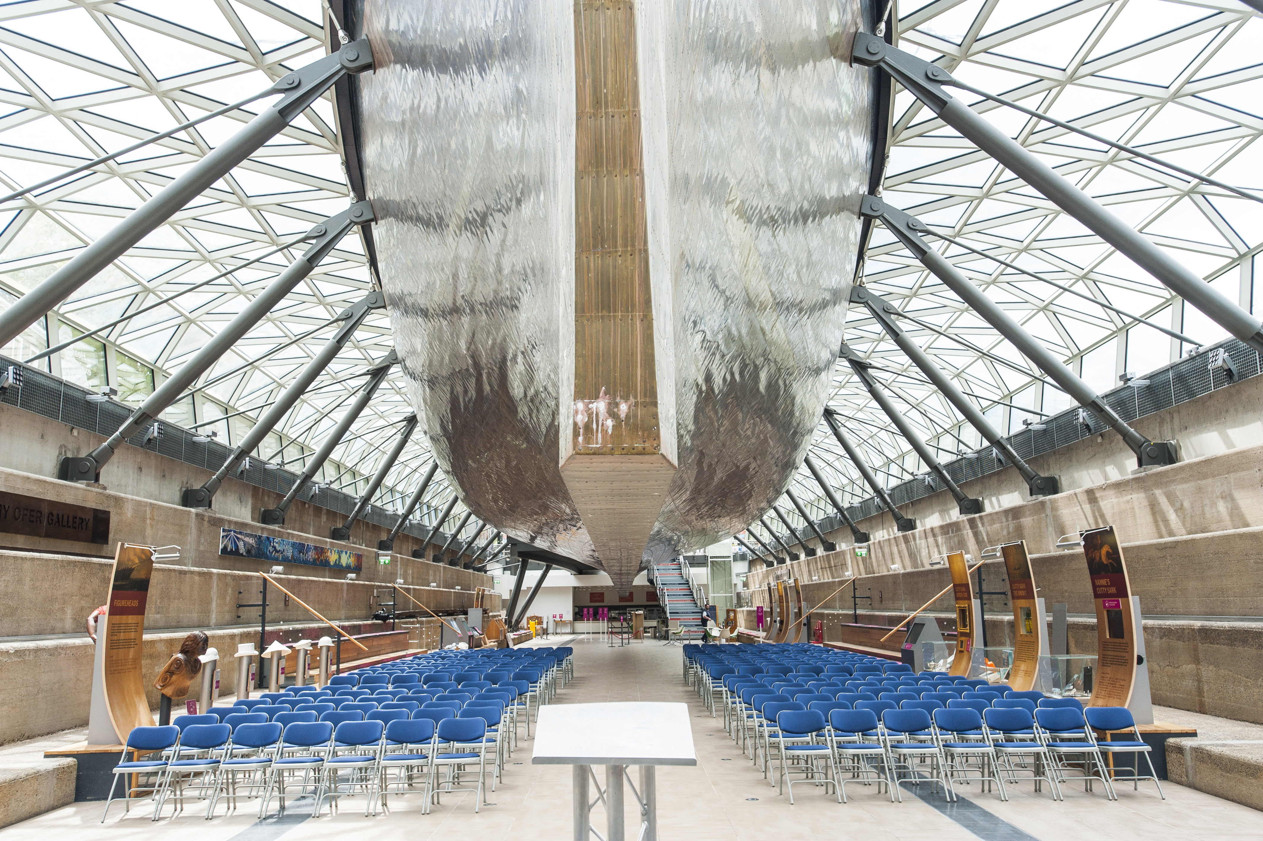 Modern event space in The Dry Berth, Cutty Sark, with boat-like architecture and blue chairs.
