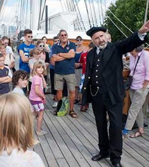 Charismatic speaker engaging diverse audience on The Weather Deck, Cutty Sark event.