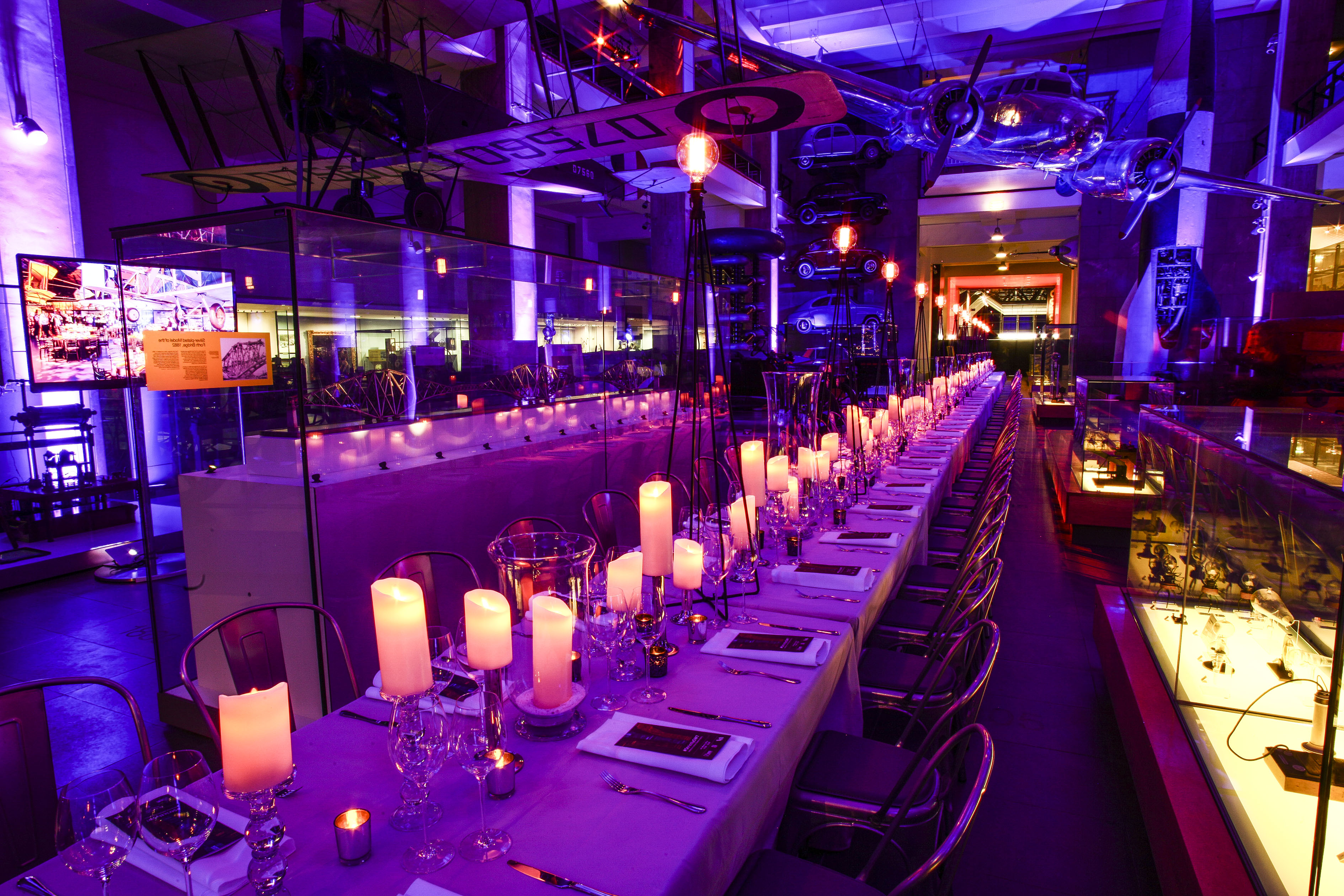 Elegant dinner setup in Science Museum, featuring vintage cars for corporate events.