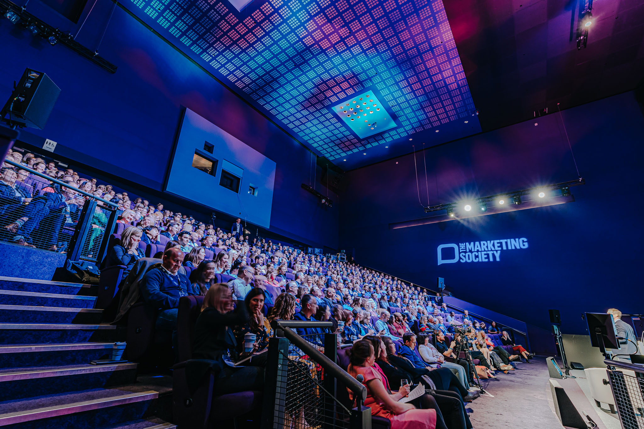 IMAX Theatre conference with engaged audience in modern auditorium setting.