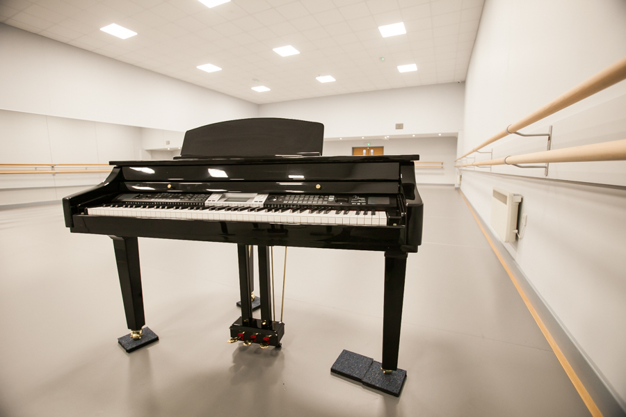 Sleek black piano in spacious dance studio for music recitals and rehearsals.