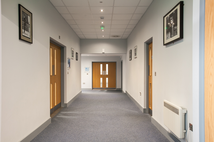 Well-lit corridor with framed artwork at Patricia Alice Studio, ideal for events and meetings.