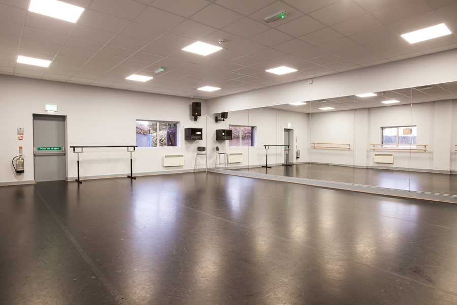 Spacious dance studio with mirrors and ballet bars for workshops and fitness classes.