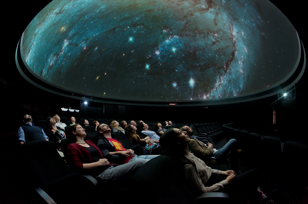 Captivated audience in Peter Harrison Planetarium during an immersive cosmic event.