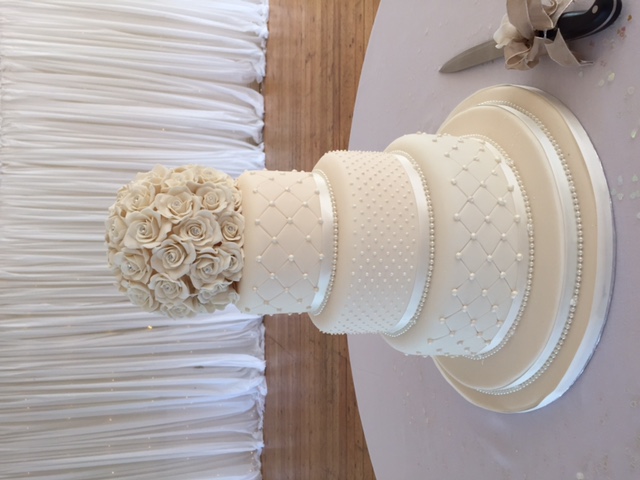 Elegant three-tier wedding cake with floral topper in The Britannia Suite, Ravens Ait Island.