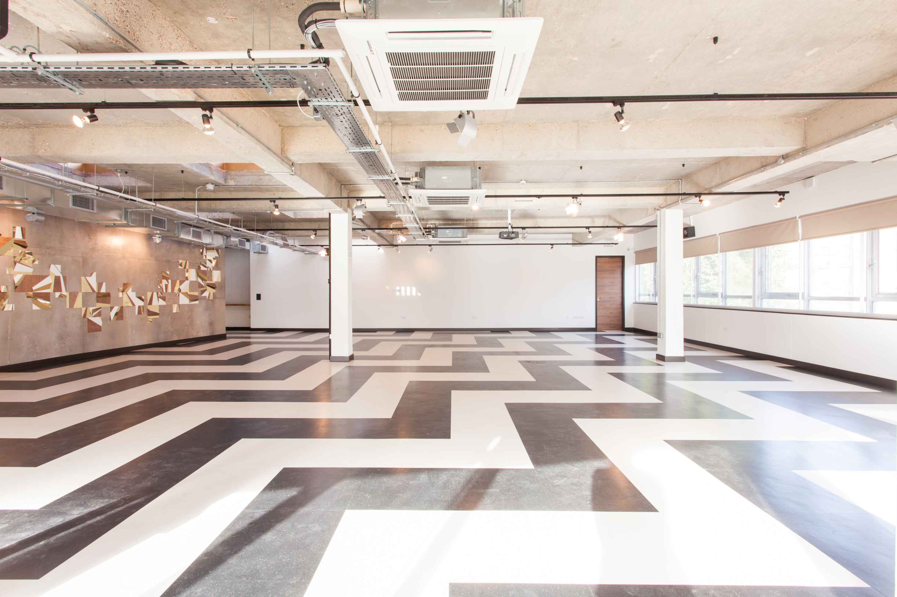 Versatile event space with geometric floor design, ideal for meetings and workshops.