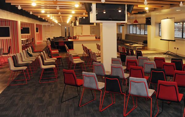 Champions Lounge at Liverpool FC, modern meeting space with red and gray chairs.