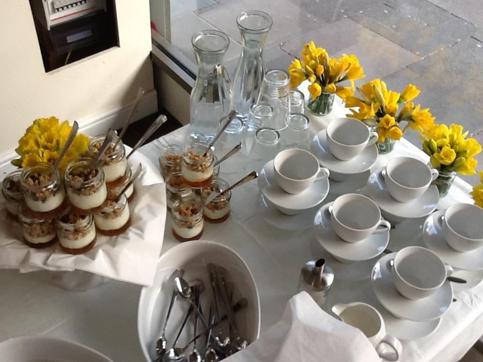 Elegant refreshment station with dessert cups and flowers for meetings or events.