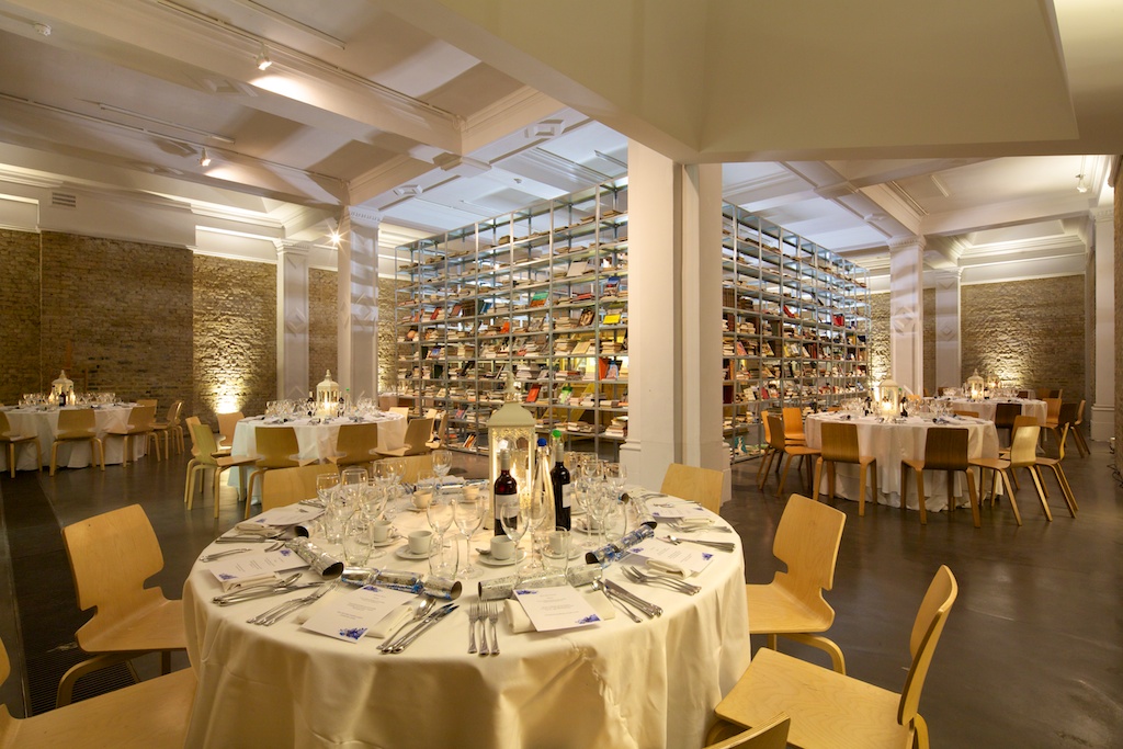 Elegant event space with round tables and stylish bookshelf for weddings and corporate events.