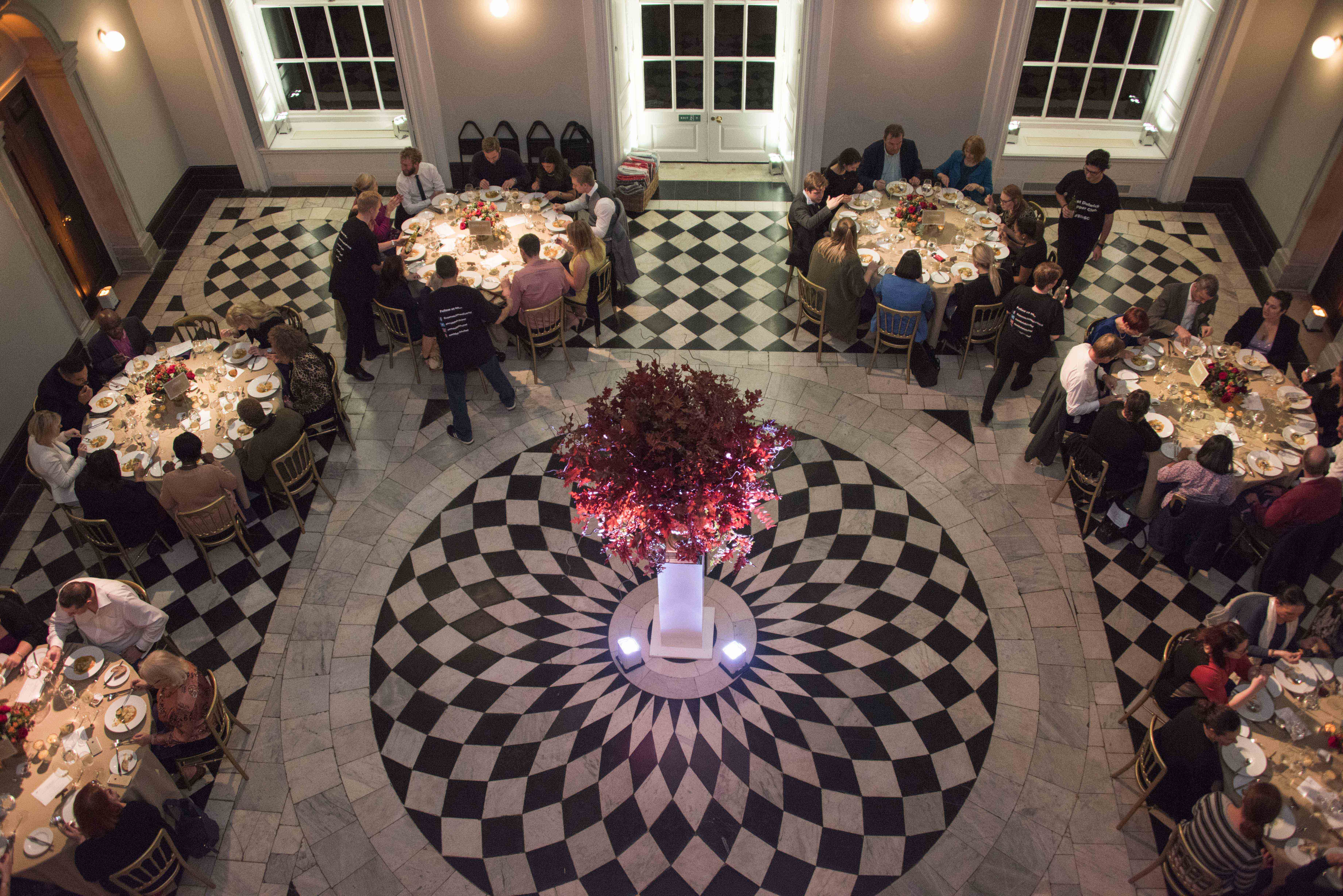 Elegant banquet in The Great Hall, Queen's House with checkered floor and floral centerpiece.