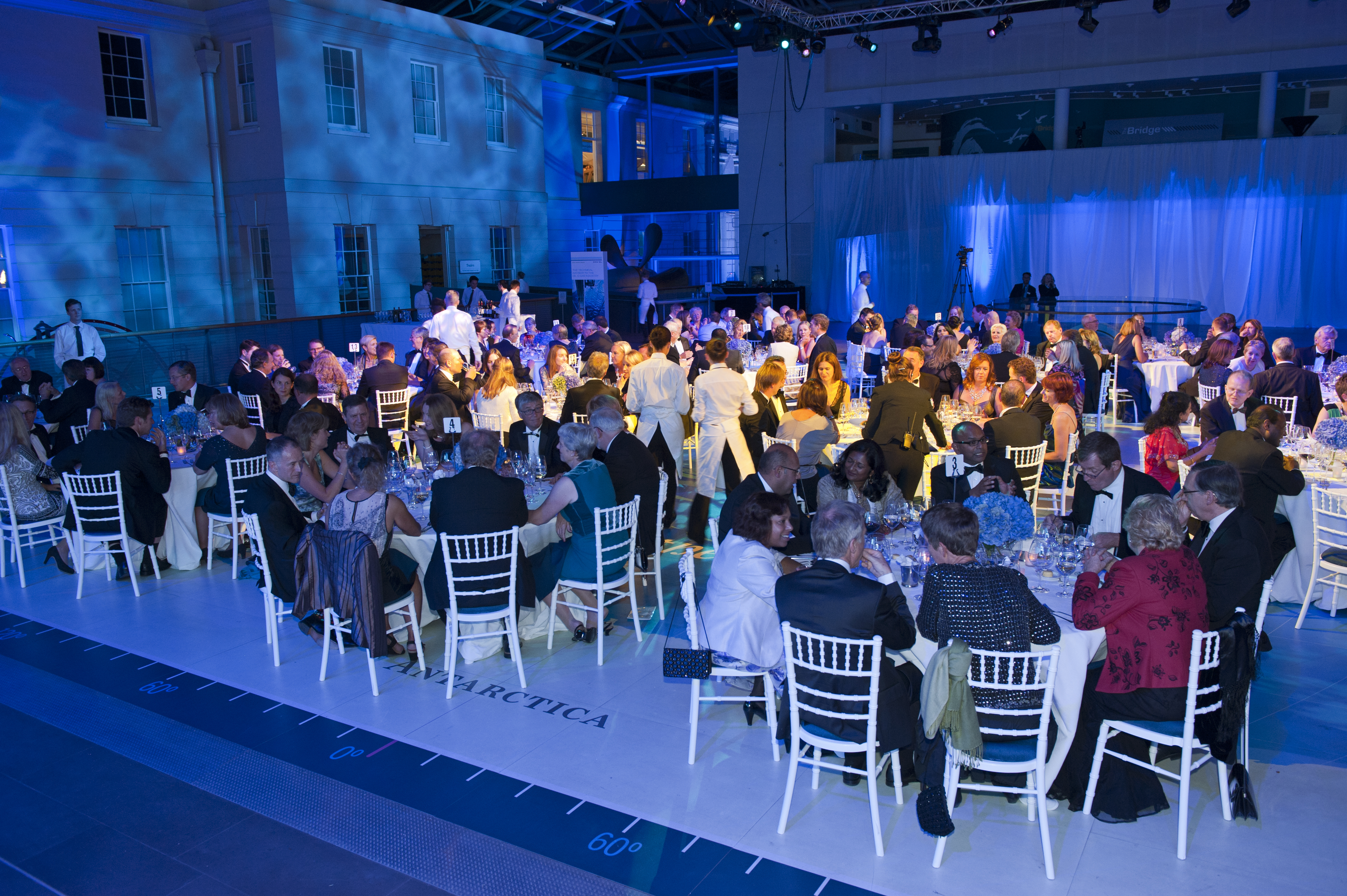 Elegant gala dinner at National Maritime Museum with formal guests and blue lighting.