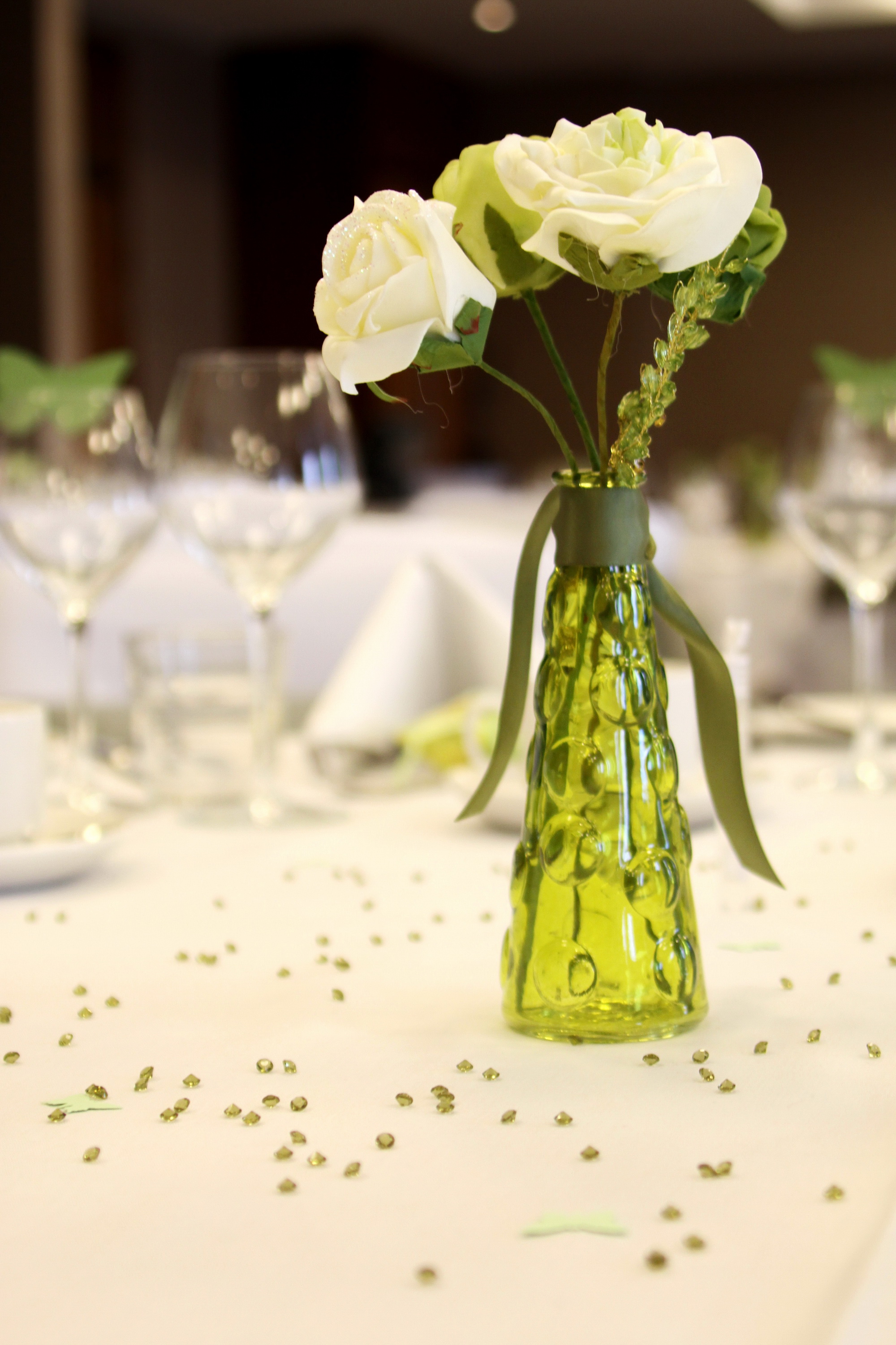 Elegant table centerpiece with green bottle and flowers at Crowne Plaza Reading East events.