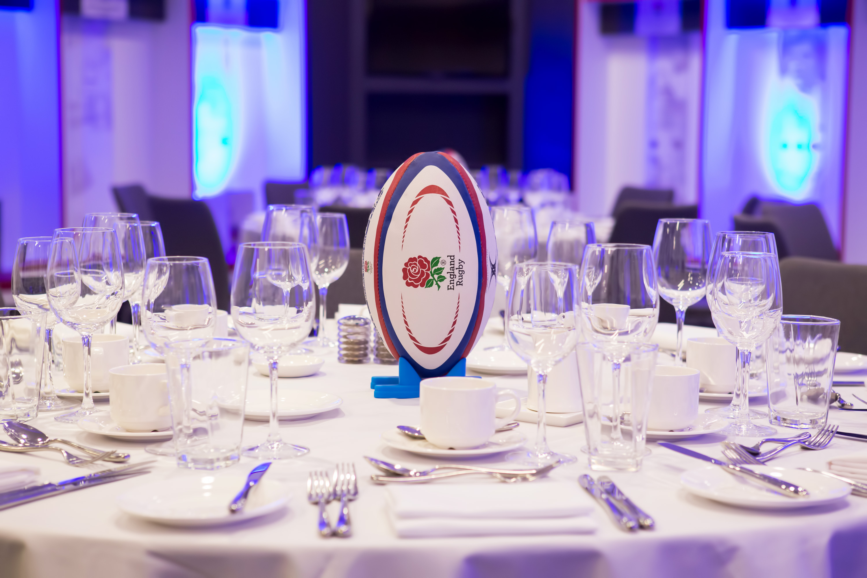 Elegant banquet table with rugby ball centerpiece at Twickenham for sports event.