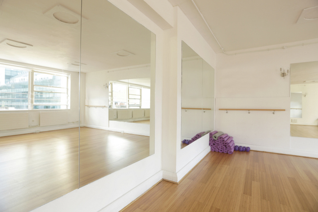 Bright studio with mirrors and wooden flooring for workshops and fitness classes in London.