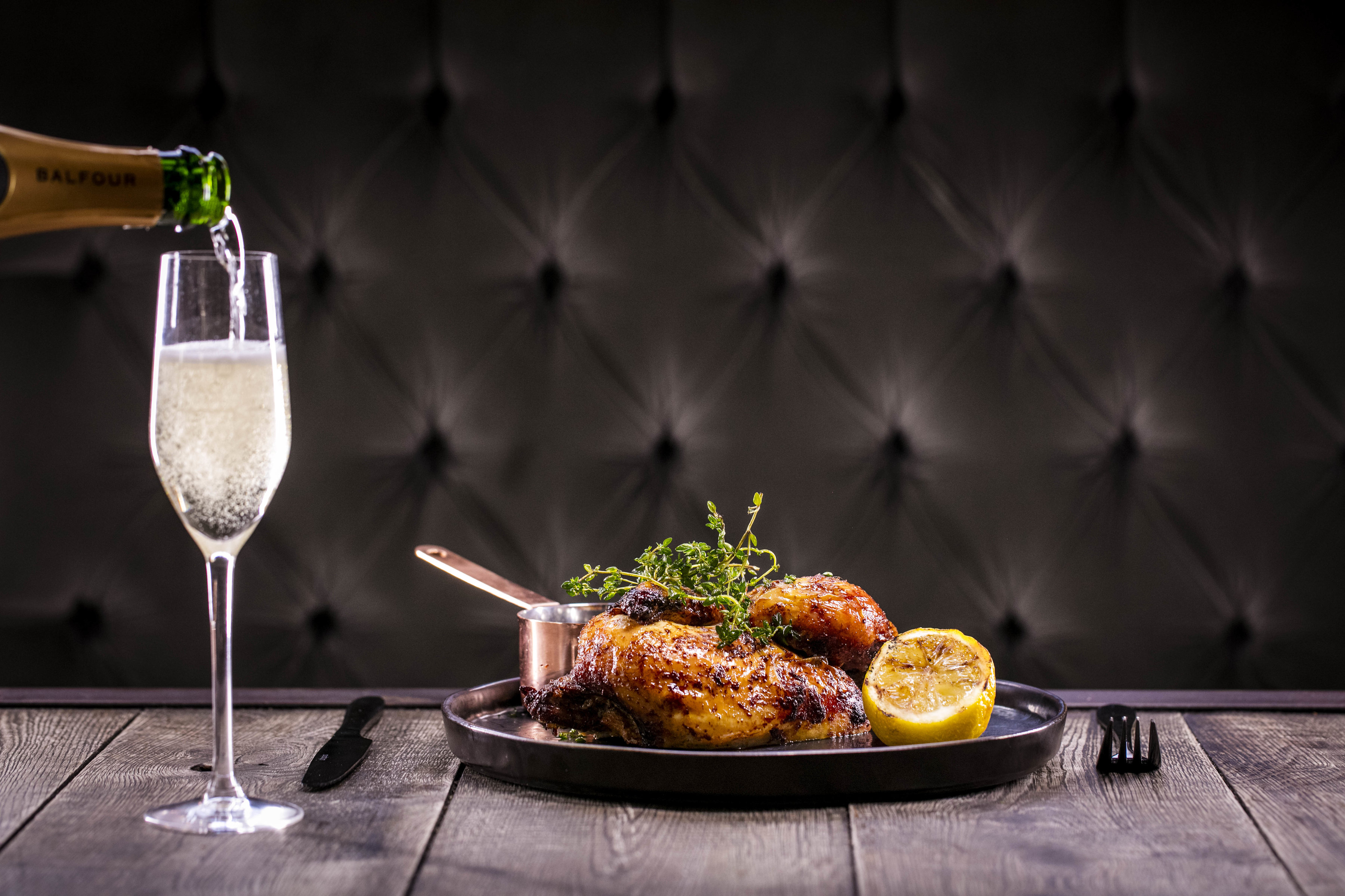 Gourmet roasted chicken dish with champagne flute at upscale dining event in Balfour St Bart's.
