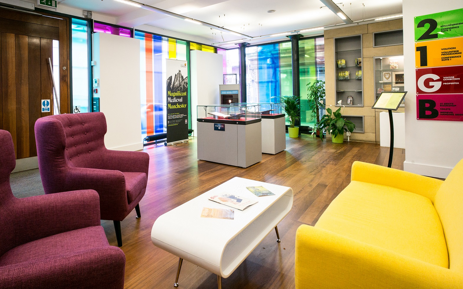 Modern meeting space with colorful glass panels at Manchester Cathedral Visitor Centre.