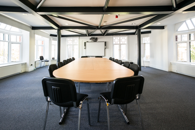 Spacious conference room with oval table at Manchester Cathedral Visitor Centre for meetings.