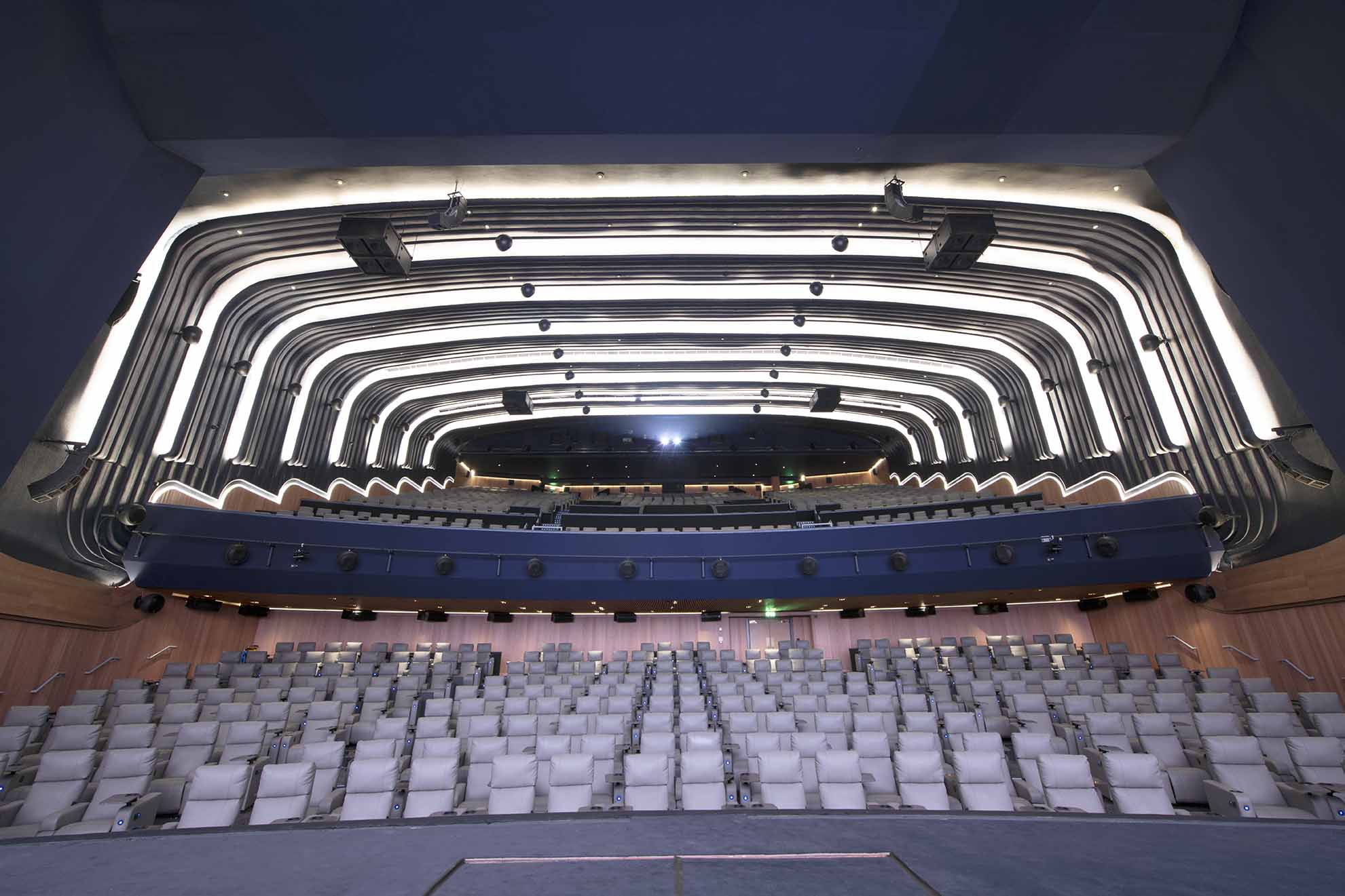 Modern auditorium with curved ceiling at ODEON LUXE Leicester Square for conferences and performances.