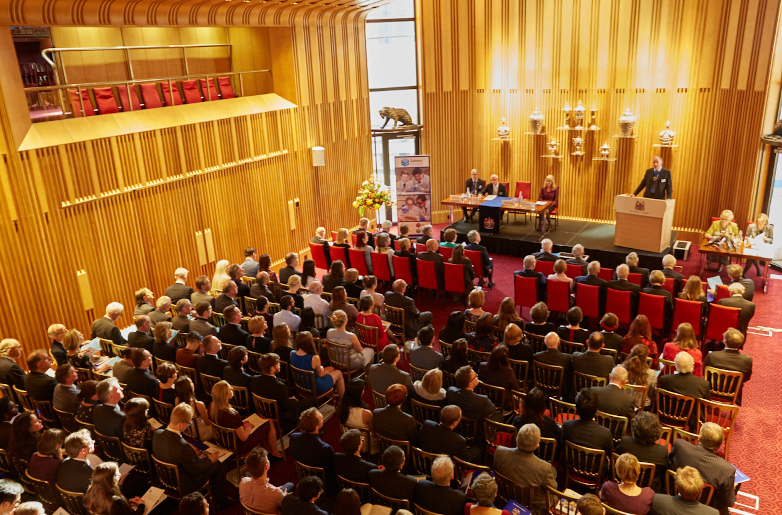 Conference in Salters' Hall with speaker addressing engaged audience in elegant venue.