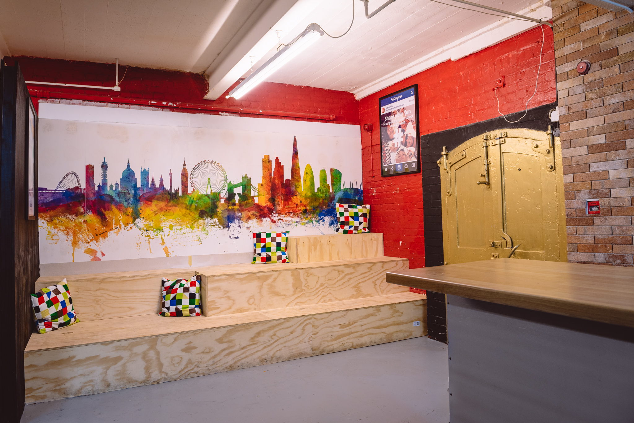 Vibrant meeting space at London Bartender School with colorful mural, ideal for team events.