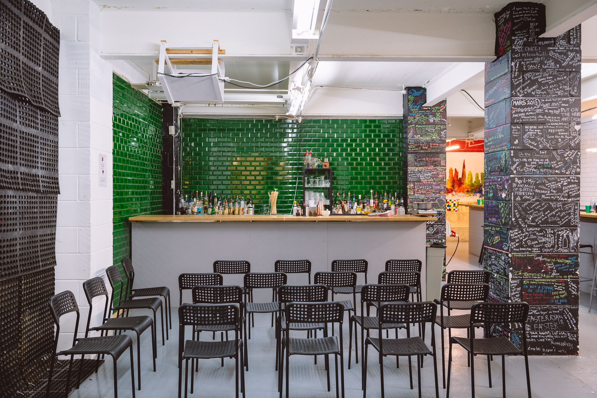 Main Room at London Bartender School with stylish bar and green tiles for events.