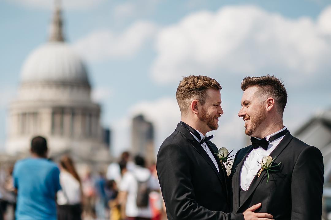 Joyful couple in formal attire celebrating wedding in The Balcony Room, urban backdrop.