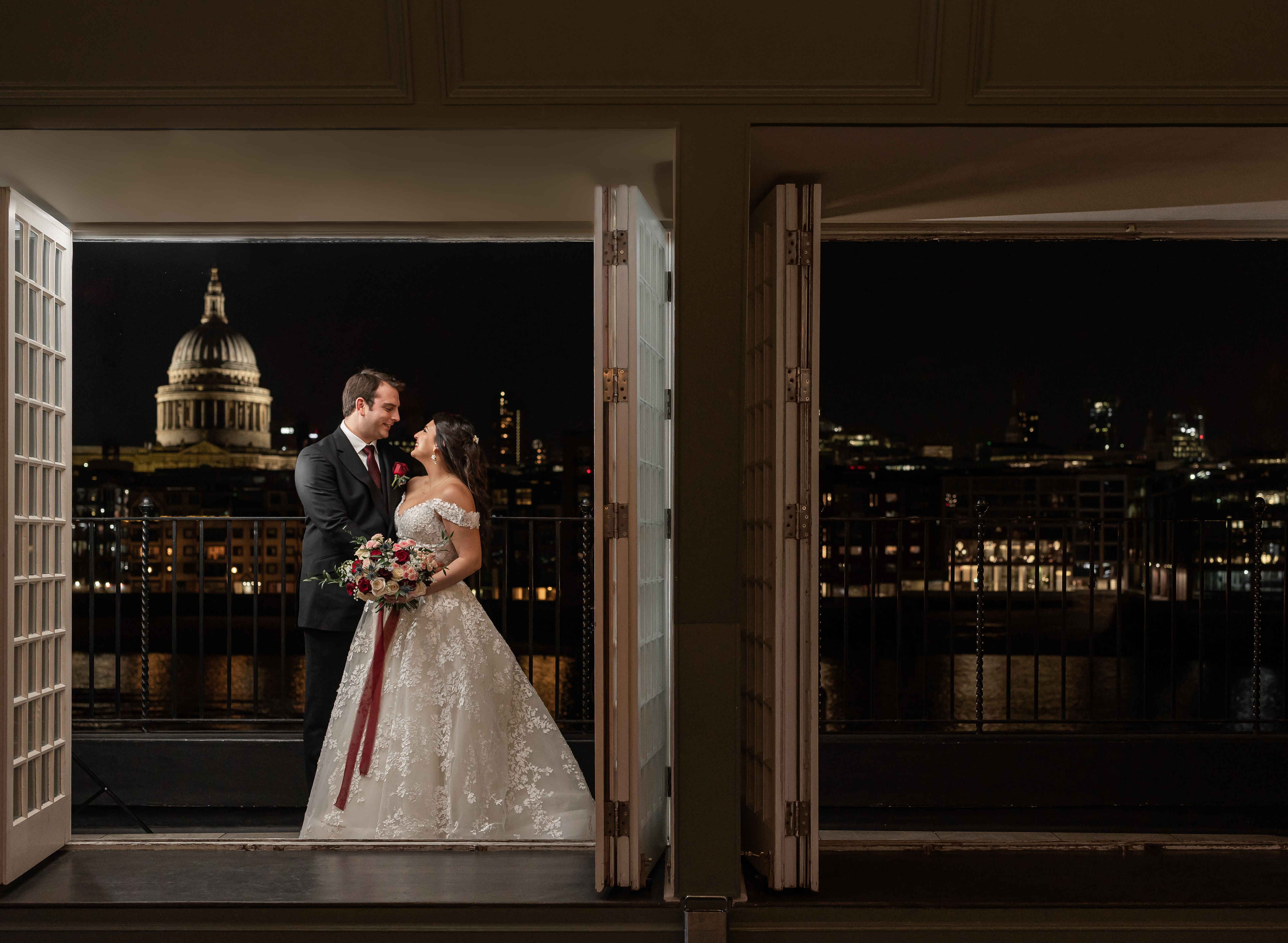 Couple in formal attire at The Balcony Room, St. Paul's Cathedral backdrop, wedding venue.