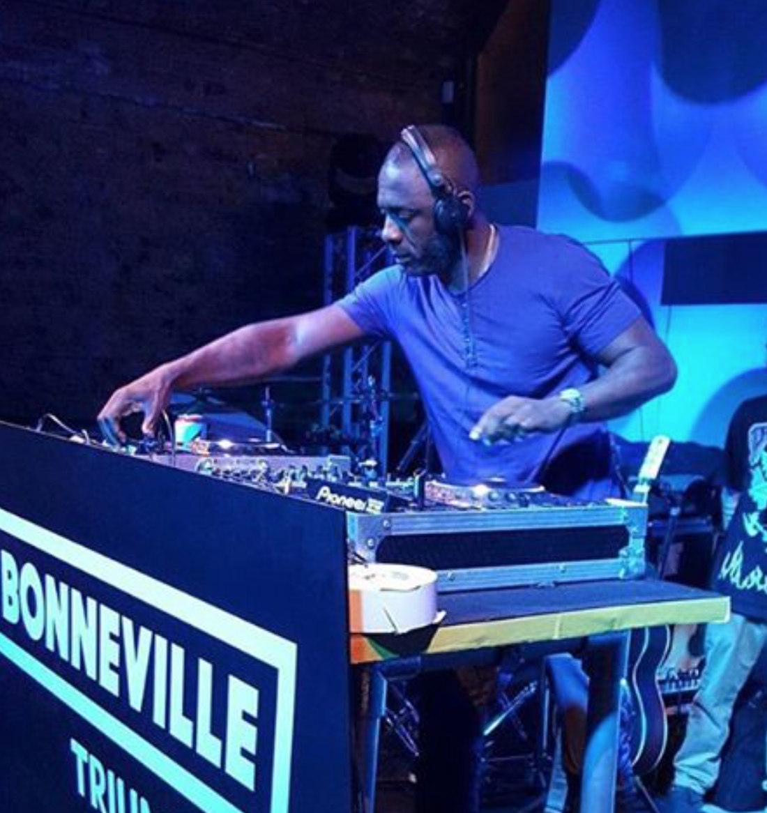 DJ mixing tracks at Arch 4 event with vibrant lighting and energetic atmosphere.