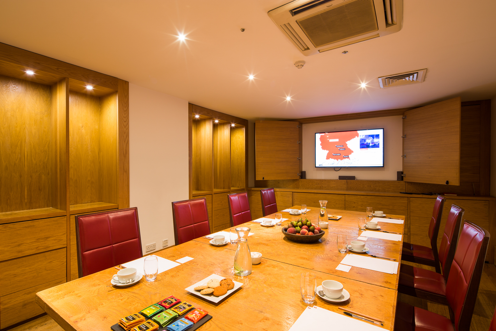 The Boardroom at Hope Street Hotel with a polished table and red chairs for meetings.
