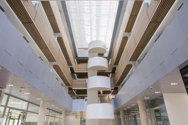 Modern auditorium atrium with spiral staircase, ideal for conferences and networking events.