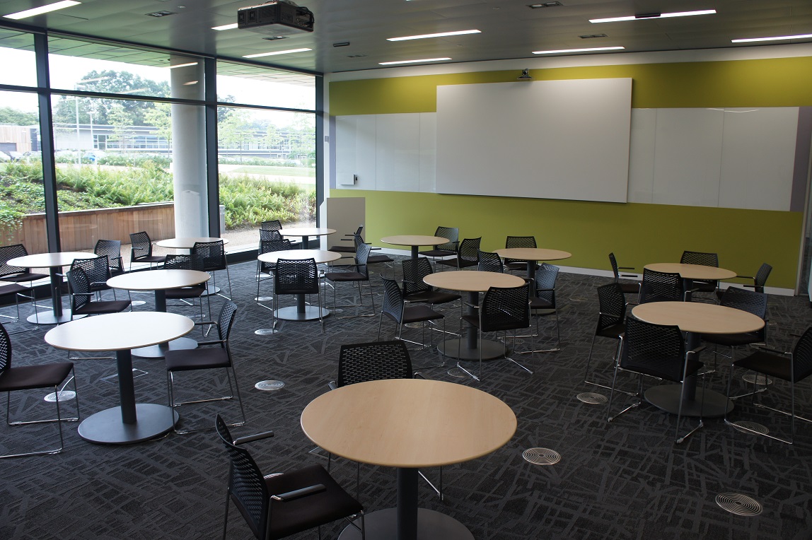 Versatile auditorium with round tables, ideal for workshops and brainstorming sessions.