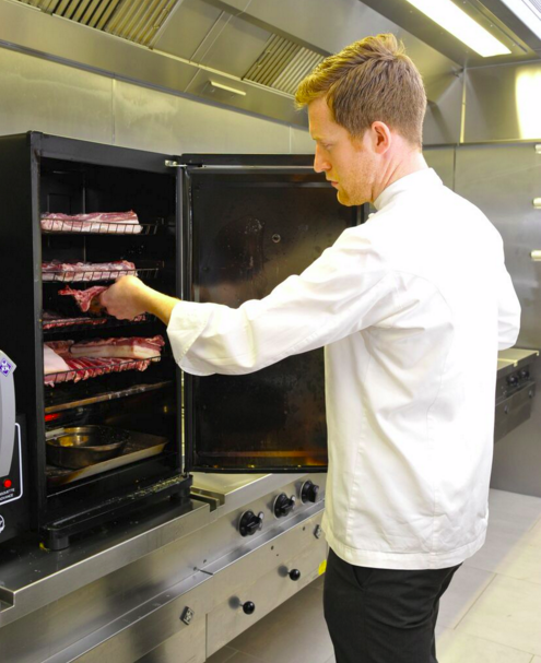Chef preparing food in Culinary Academy kitchen for quality catering events.