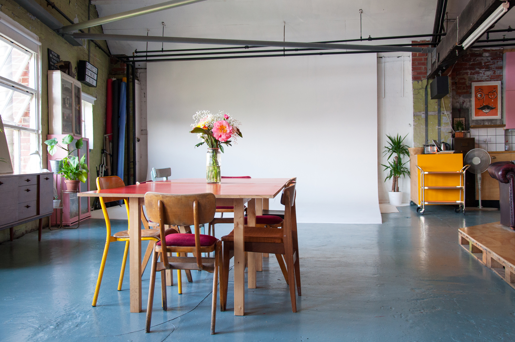 Versatile event space with large table, colorful chairs for workshops and meetings.