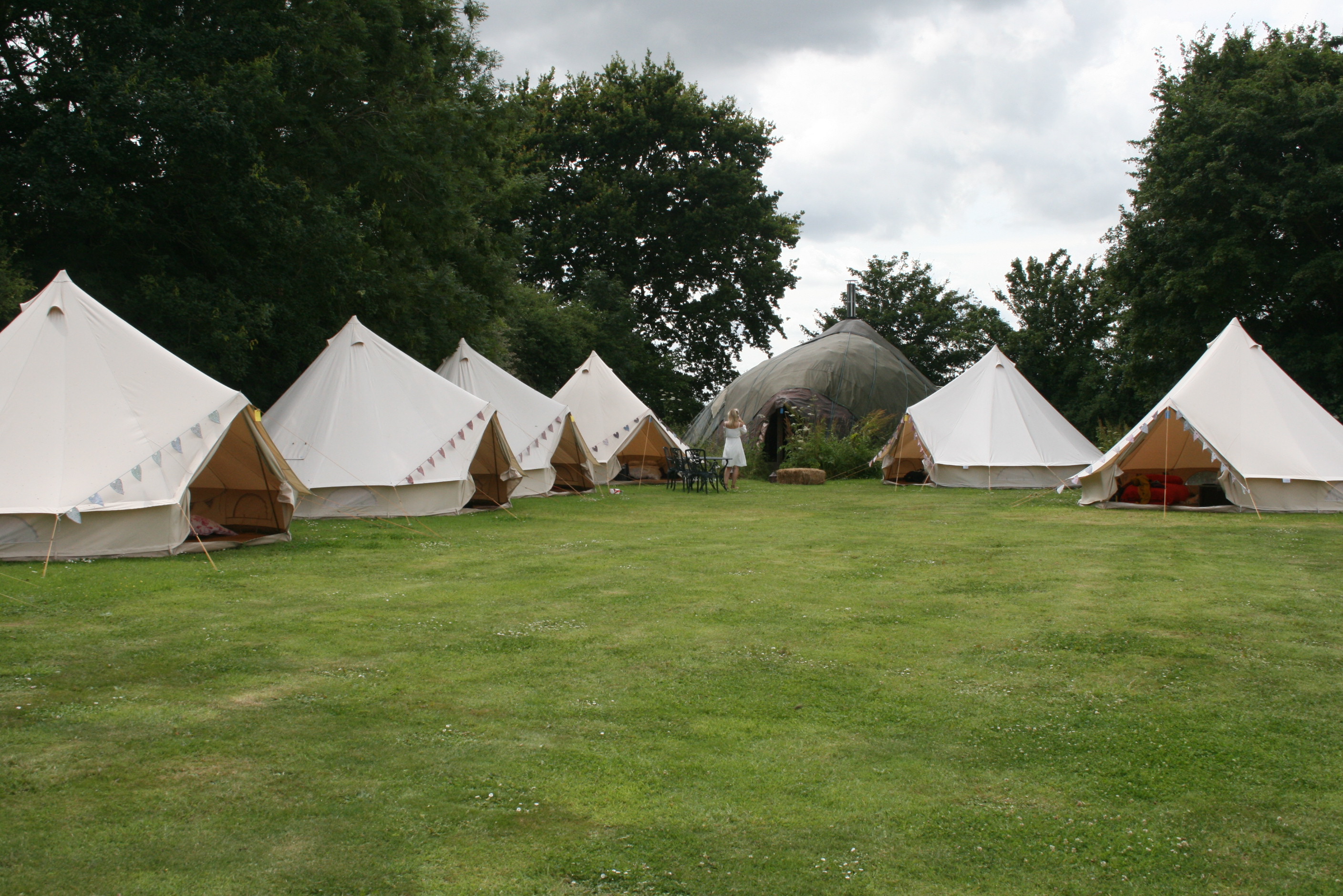 White bell tents in lush Camping Meadow for unique outdoor events and retreats.