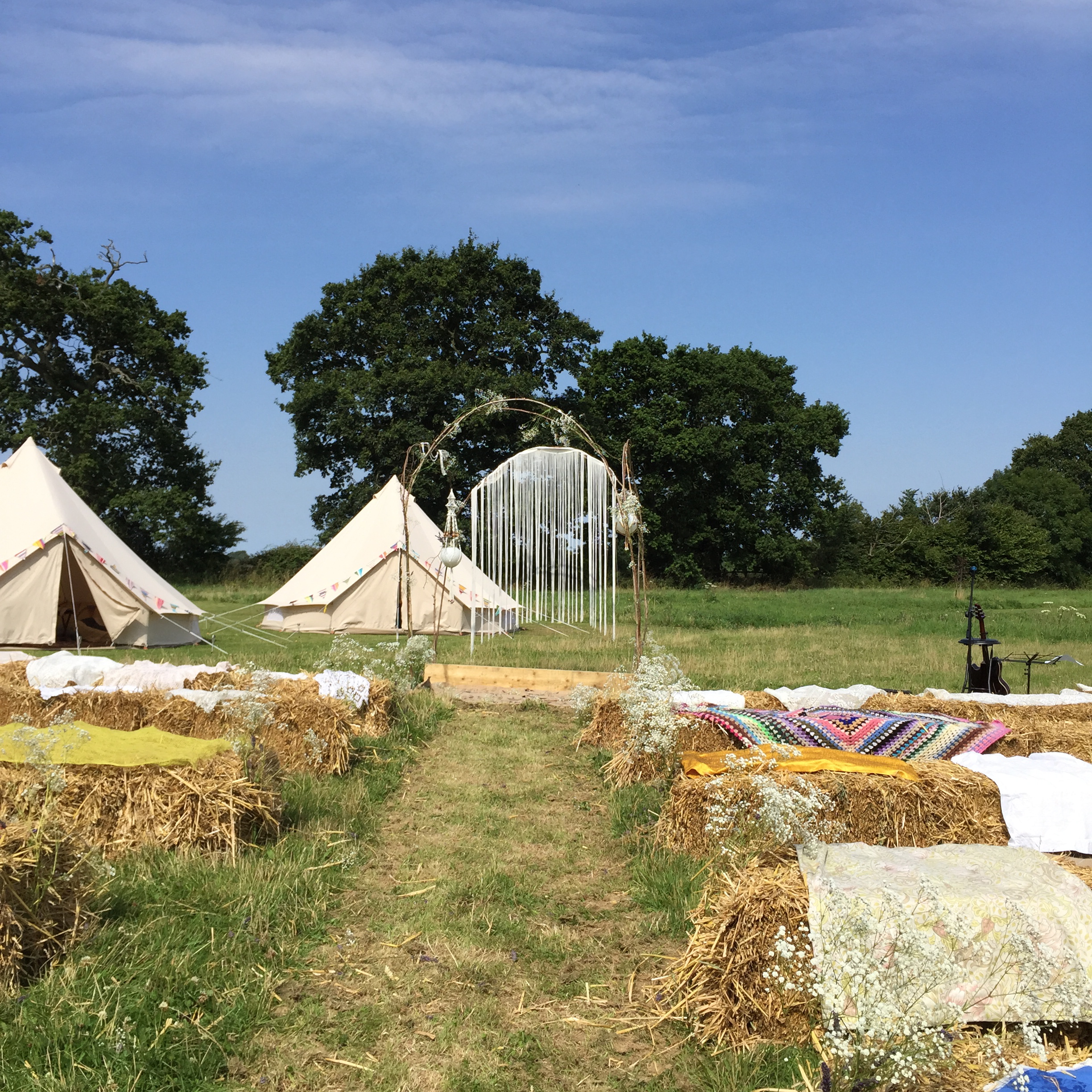 Glamping tents and hay bale seating at Camping Meadow for outdoor events.