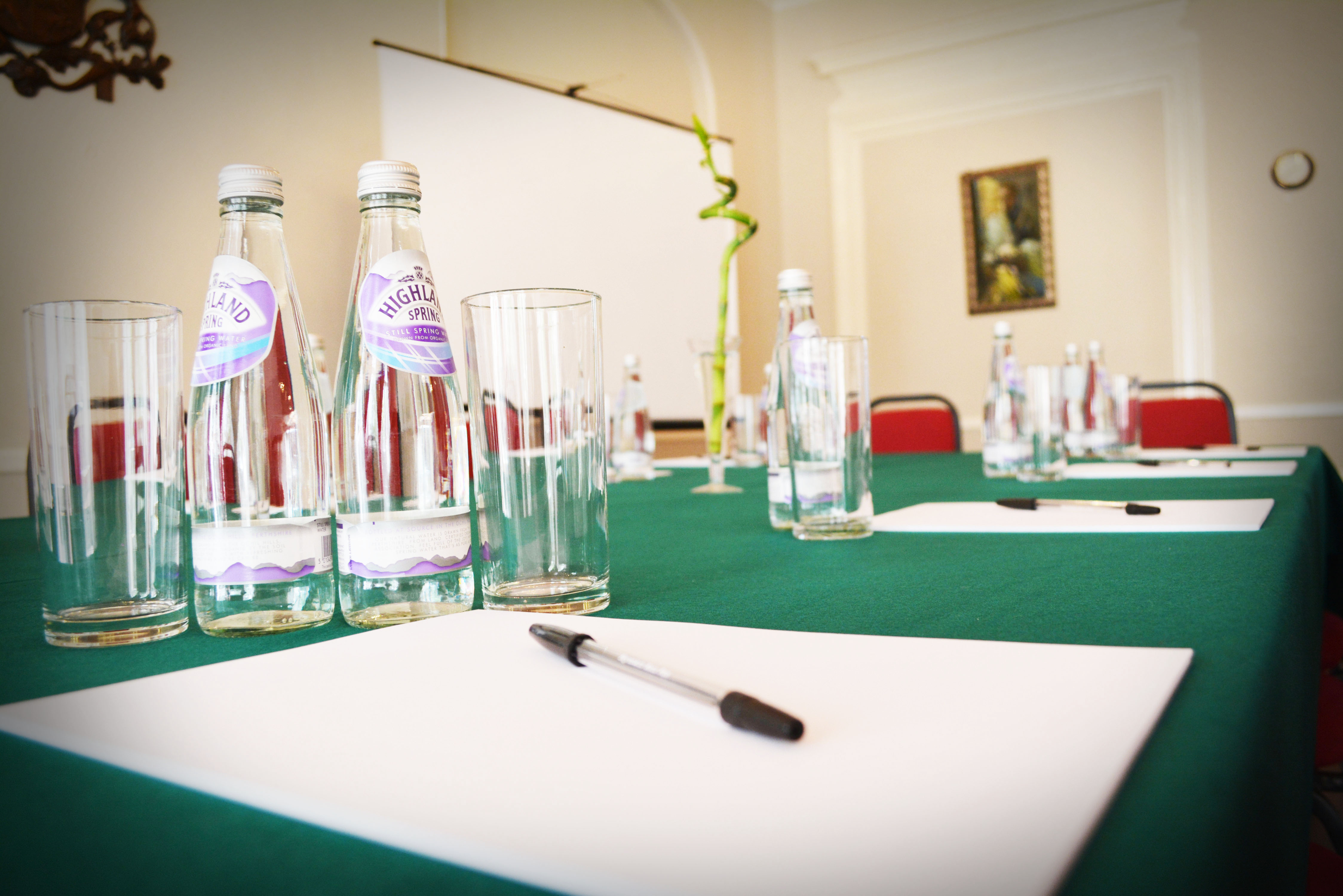 Queensborough Hall meeting setup with green tablecloth, water bottles, and notepads.