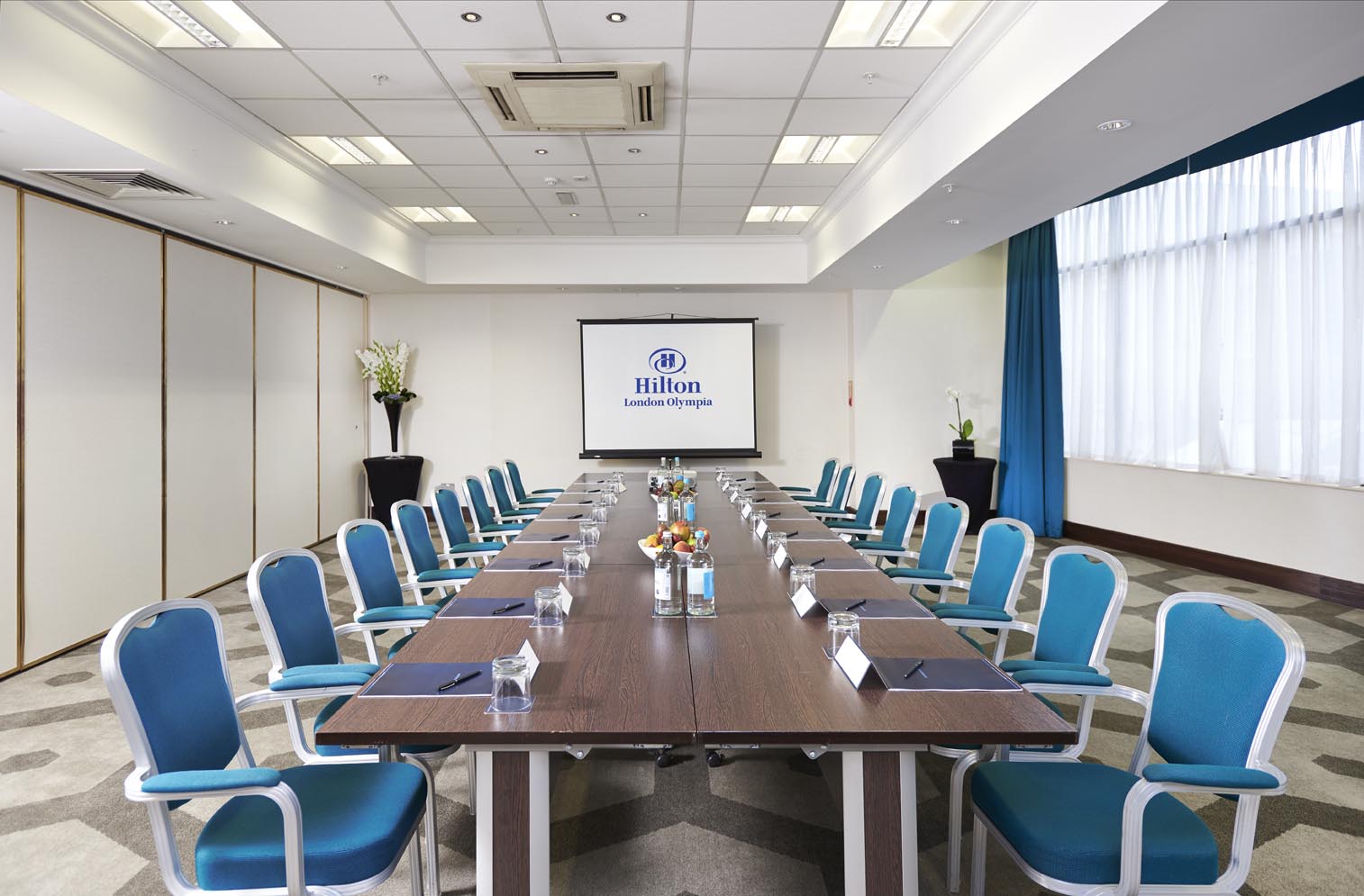 London Room at Hilton Olympia: modern meeting space with blue chairs for professional events.