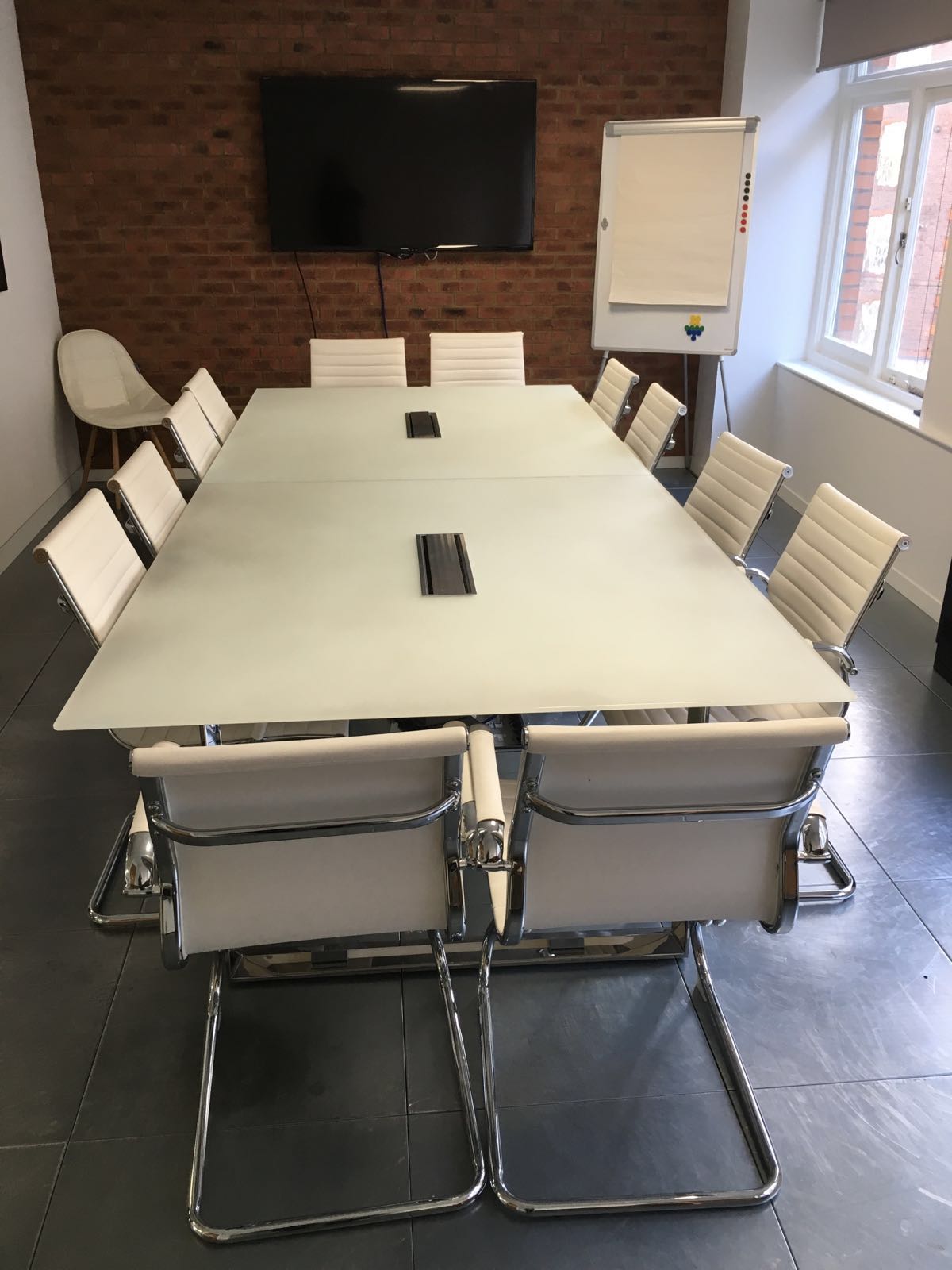 Modern conference room with glass table and white chairs, ideal for meetings and events.