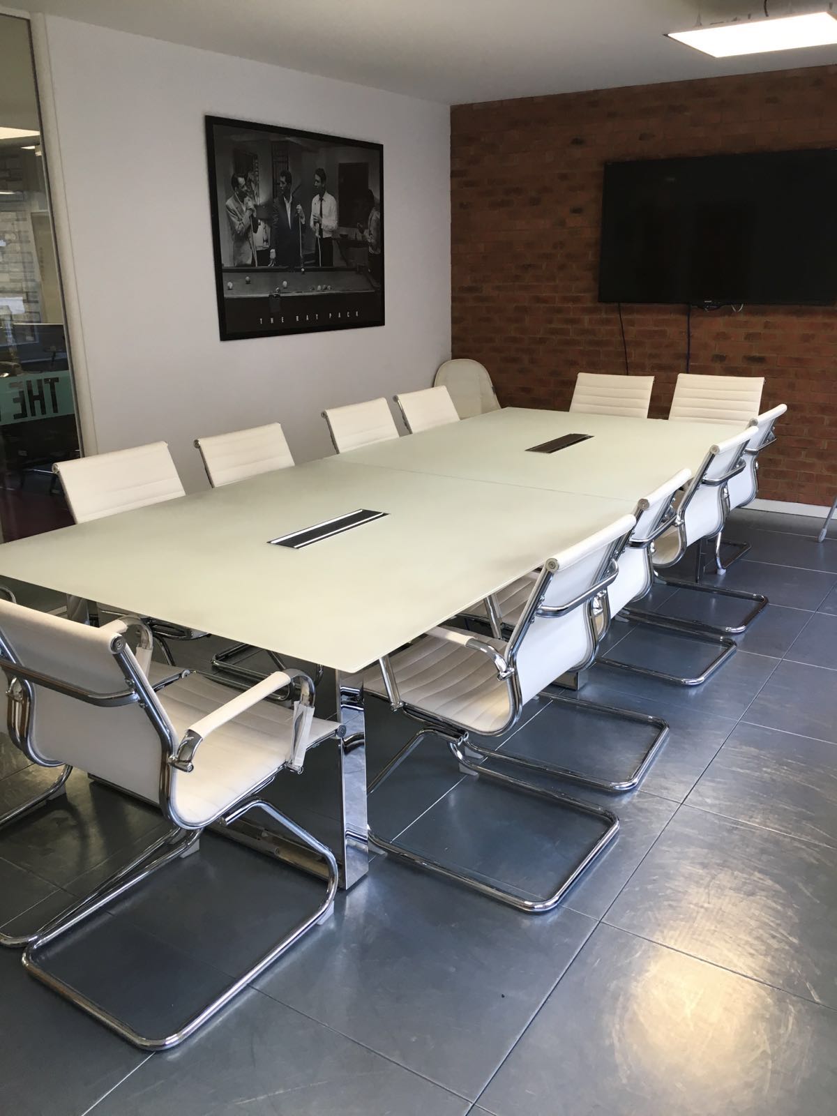 Modern conference room with glass table and white chairs for professional meetings.
