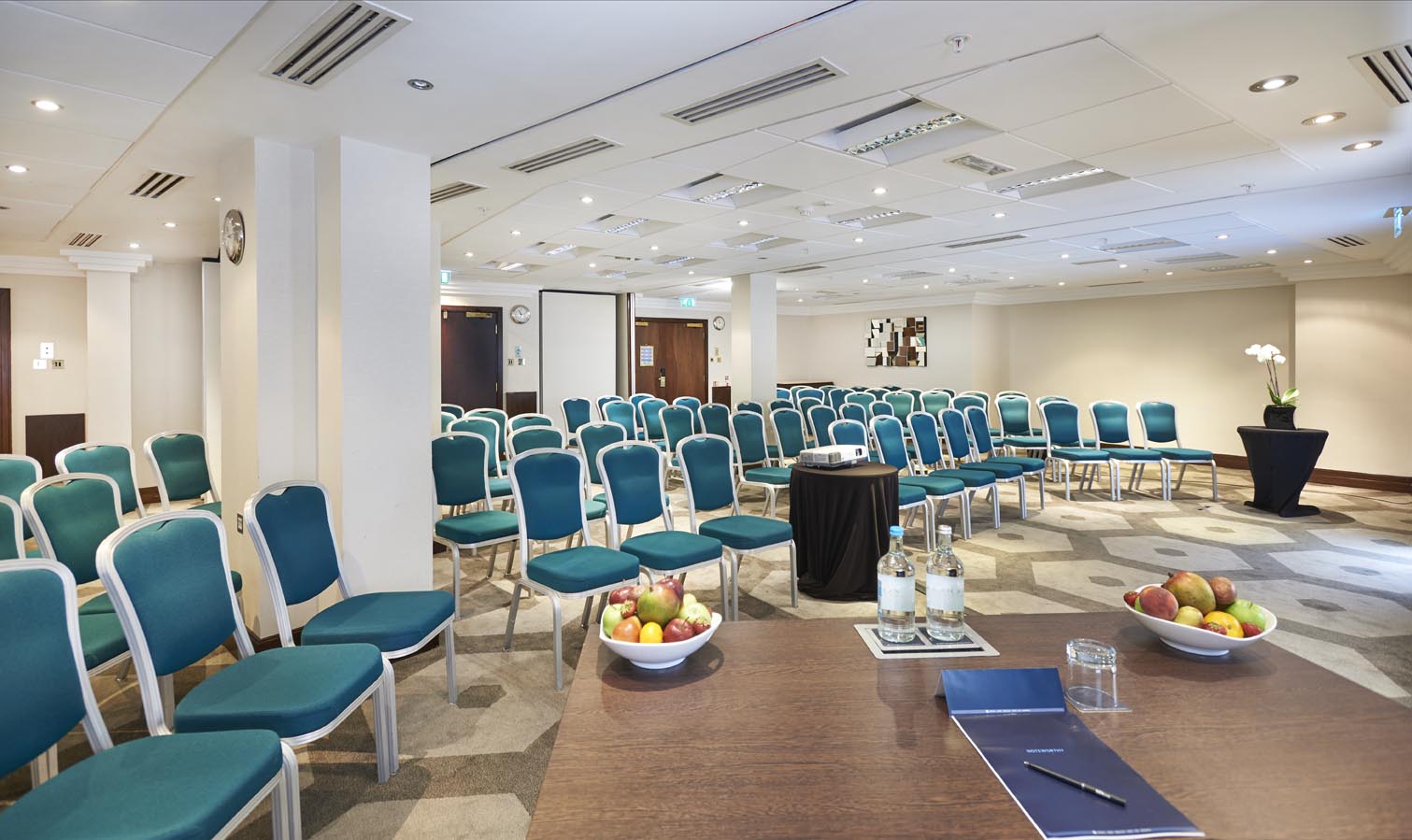 Kensington Suite at Hilton London Olympia, modern meeting space with teal chairs.