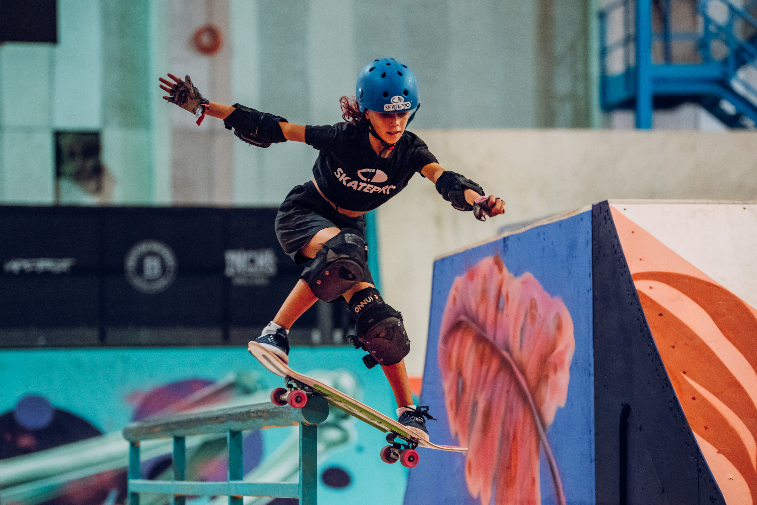 Young skateboarder performing a trick in vibrant skate park at youth sports event.