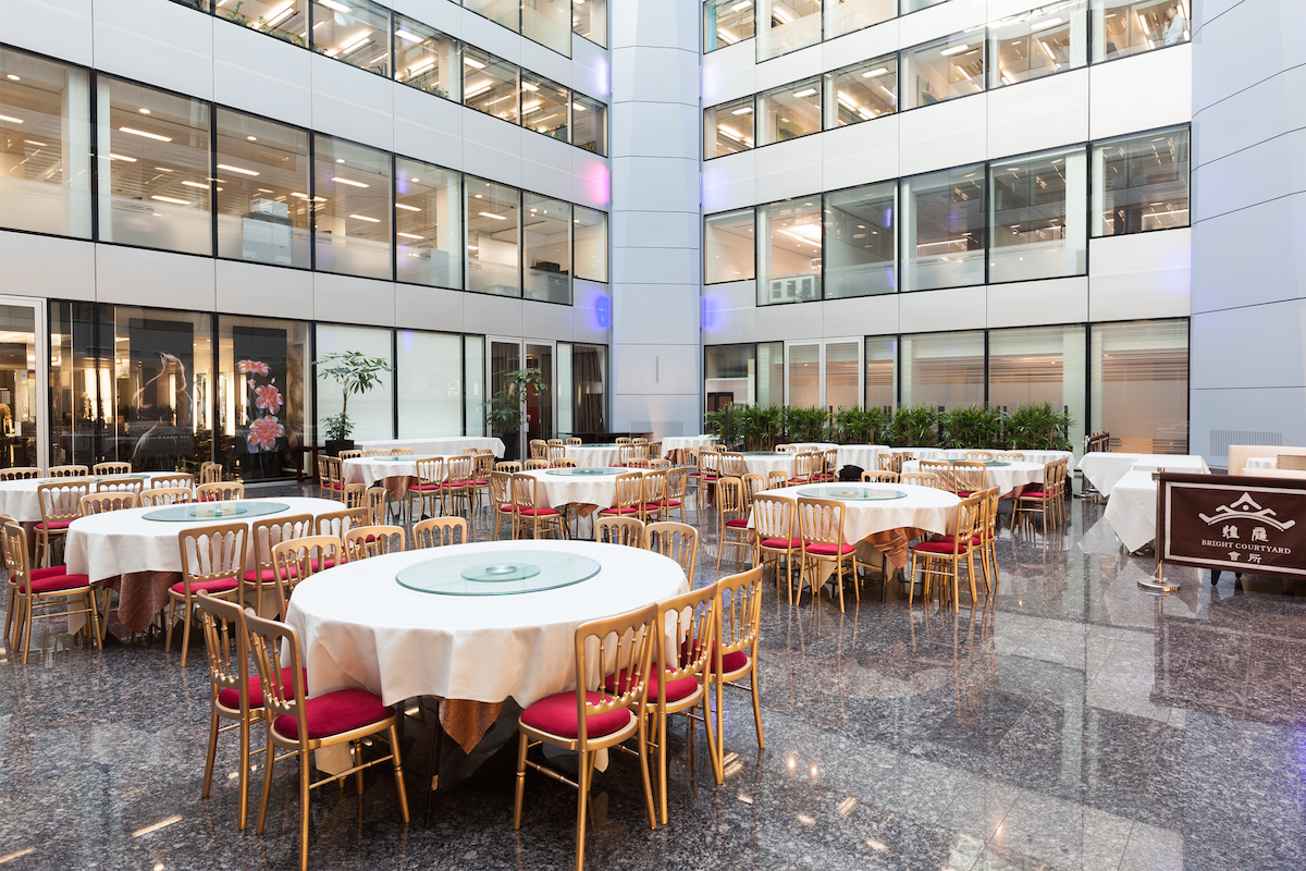 Bright Courtyard Club event space with round tables, perfect for corporate meetings or gatherings.
